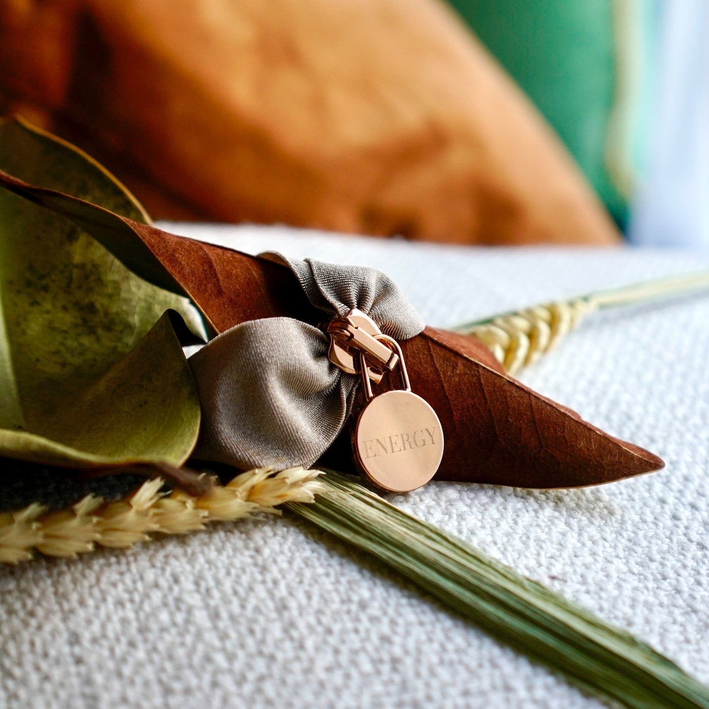 Engraved Energy Bracelet with rose gold charm on textured fabric background