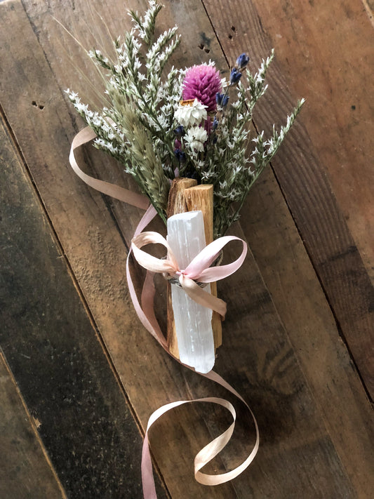 Uplifting Palo Santo Selenite floral bouquet with pink, white, and yellow dried flowers and tied with a pink ribbon on wooden background