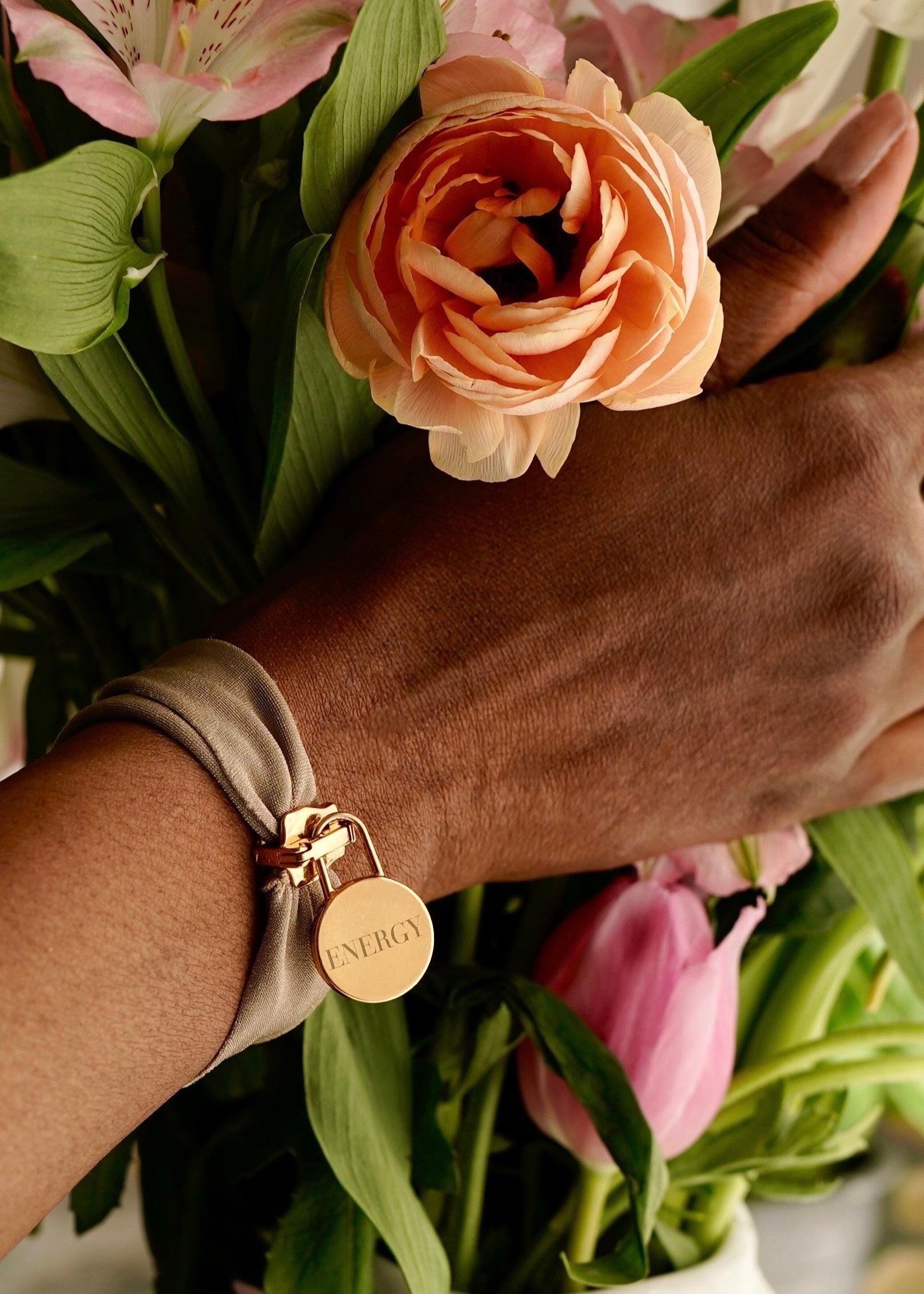 engraved energy bracelet on wrist with flowers in background handcrafted Italian jewelry for mindfulness and energy alignment