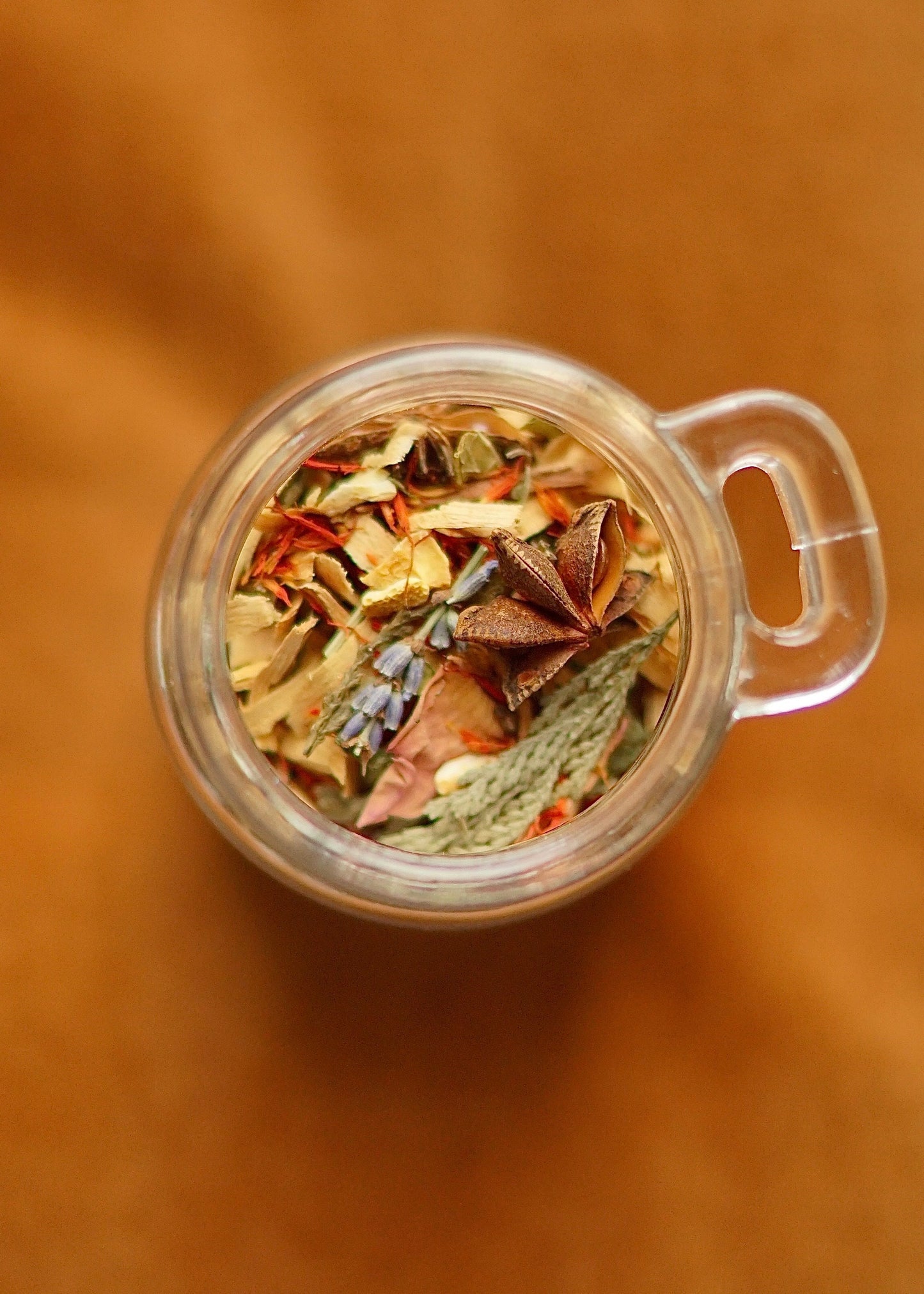 Top view of EverKindle Kindle & Simmer Autumn Incense blend in glass cup with star anise and dried herbs