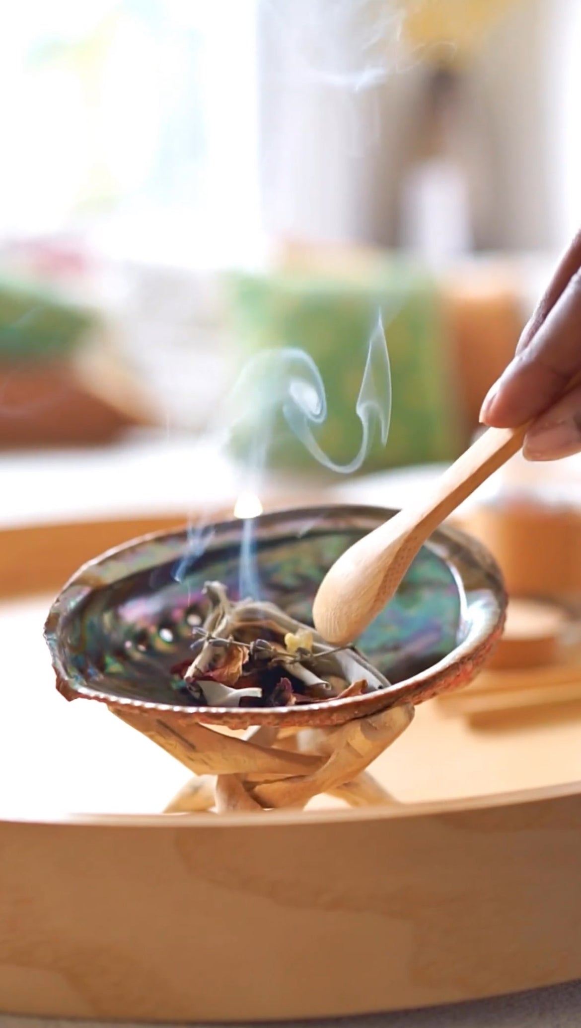 Abalone shell on wooden stand used for burning herbal incense and smudging rituals with rising smoke
